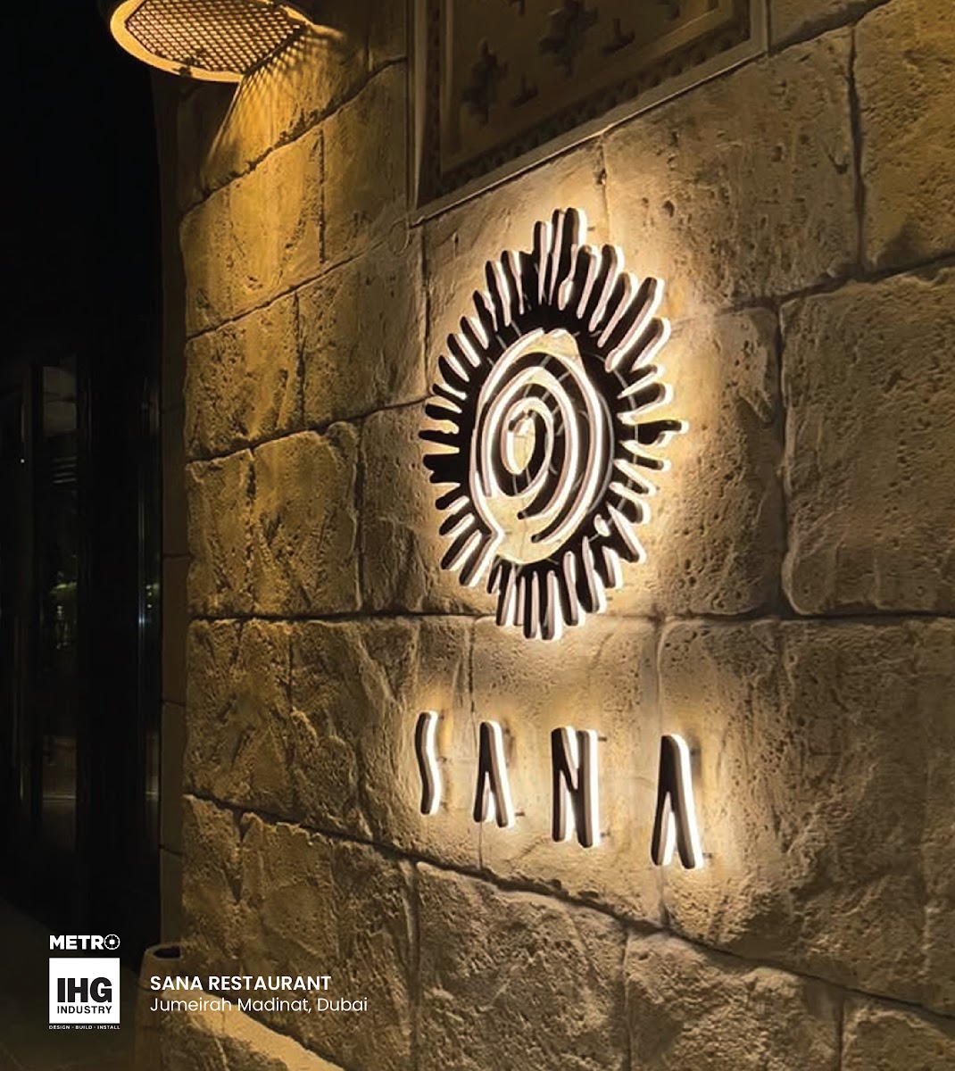 Backlit Sun-Emblem Logo on Stone Facade - Metroplus detail view