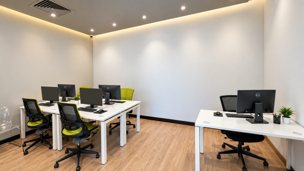 Bright open workstation room with white desks and green task chairs at Metroplus head office