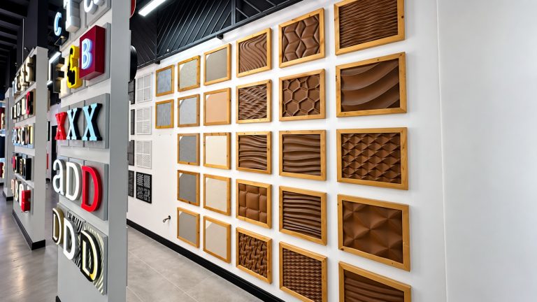 Wall of framed 3D textured panel and perforated metal finish samples in the Metroplus showroom