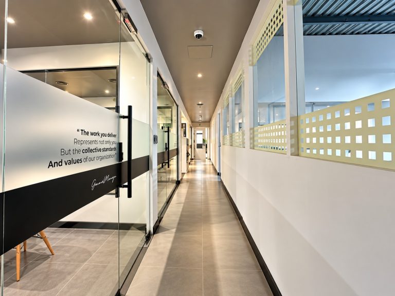 Glazed office corridor with a frosted glass values quote at the Metroplus Jebel Ali head office