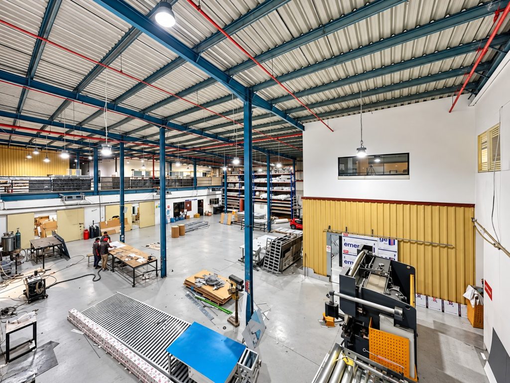 Double-height Metroplus fabrication hall with steel frame, assembly tables and press equipment