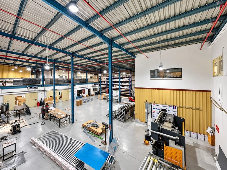 Double-height Metroplus fabrication hall with steel frame, assembly tables and press equipment