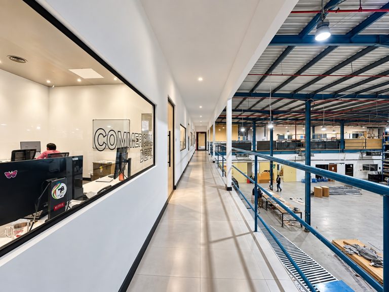 Mezzanine corridor with office windows overlooking the Metroplus factory floor