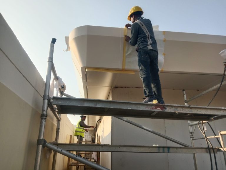 Metroplus installer working on a curved facade element from a scaffold