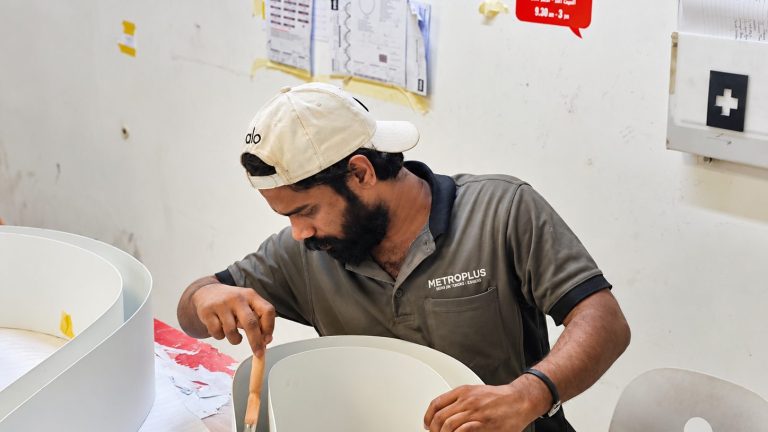 Craftsman finishing curved white sign panels at the Metroplus production facility