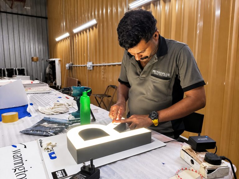 Metroplus technician assembling an illuminated channel letter in the Dubai signage workshop