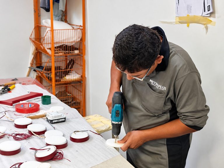 Metroplus technician drilling and assembling LED lighting components