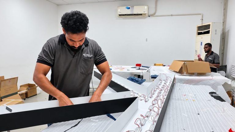 Technician fitting LED modules into a sign box at the Metroplus workshop