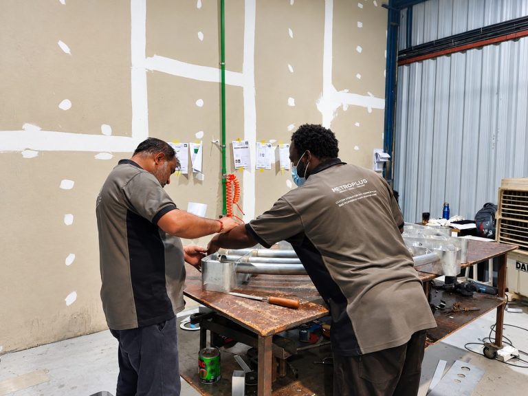 Metroplus fabrication team assembling a metal sign frame at the workbench