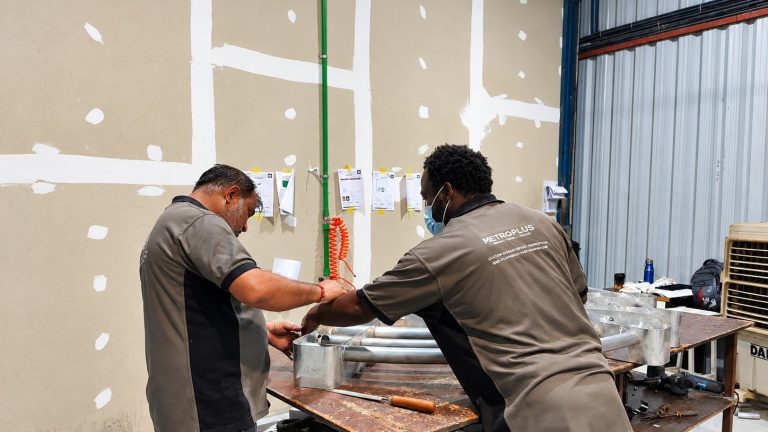 Metroplus fabrication team assembling a metal sign frame at the workbench