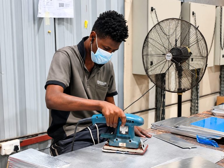 Metroplus metalworker sanding aluminium sign components in the workshop